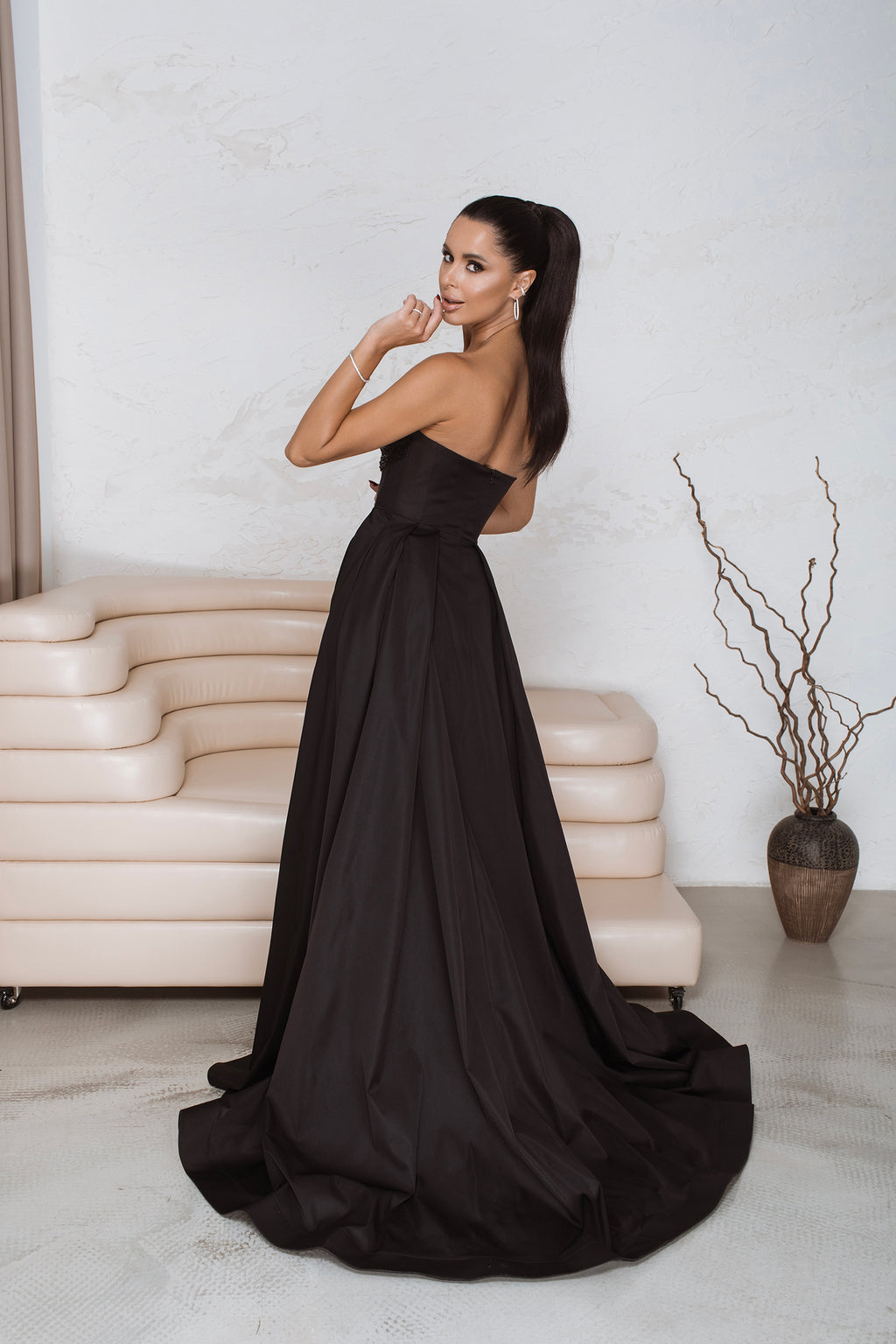 Full-length back view of black corset maxi dress showing concealed zip and dramatic train