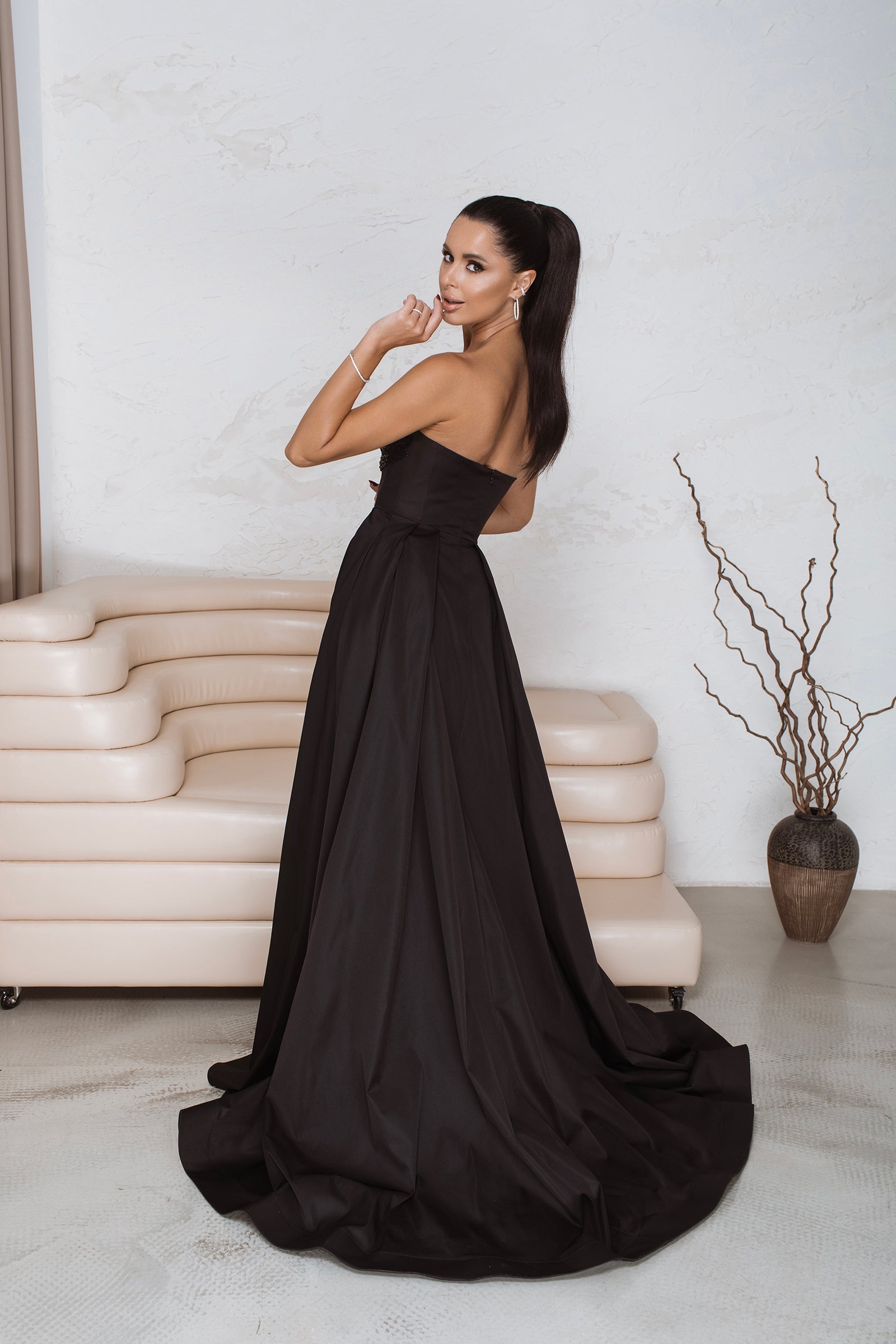 Full-length back view of black corset maxi dress showing concealed zip and dramatic train